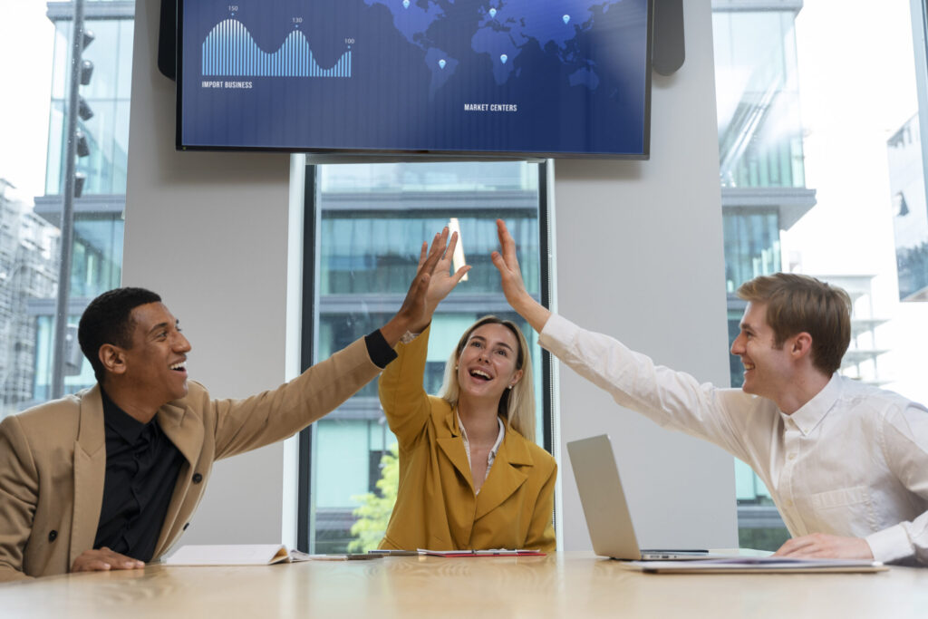 A team of colleagues celebrating a successful marketing strategy during a meeting, symbolizing a profitable funnel ready to scale with increased traffic and optimized ads.