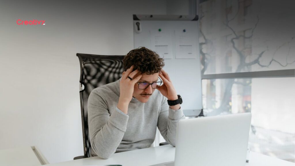 A frustrated founder sitting at a desk with hands on his head, struggling with a manual outbound sales process.