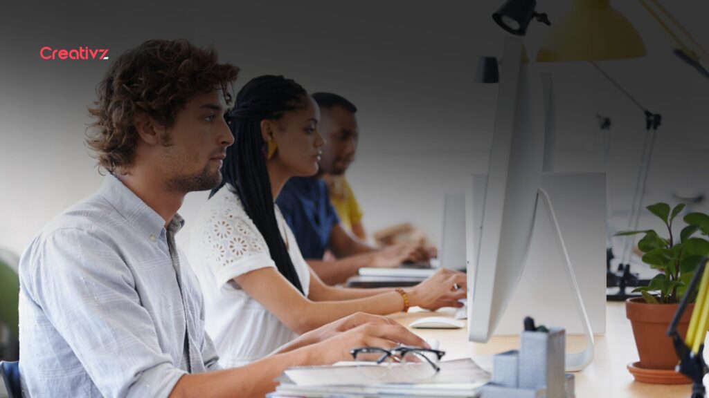 Business team working at desktop computers in a modern office, representing employees using digital tools and business software.